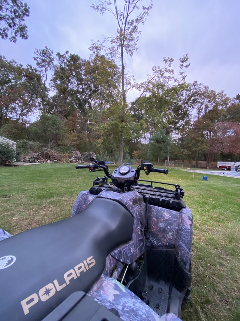Camouflage Polaris ATV in a yard.